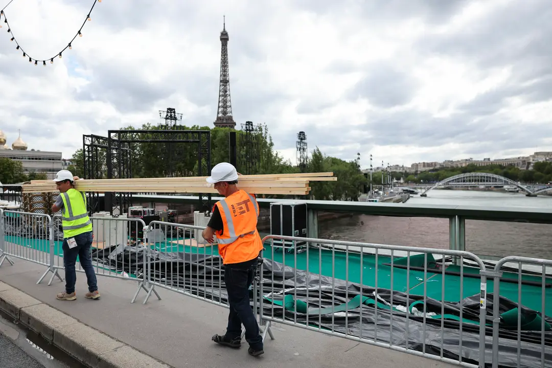 Varios operarios pasan ante el r&iacute;o Sena de Par&iacute;s, este martes. El Sena ser&aacute; el escenario elegido para la ceremonia de inauguraci&oacute;n de los Juegos Ol&iacute;mpicos el pr&oacute;ximo viernes 26 de Julio. EFE/ Miguel Gutierre